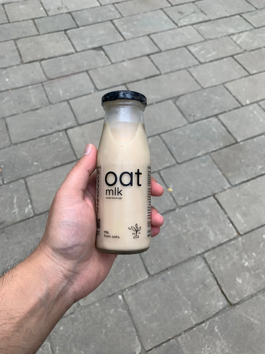 Portable 200ml glass bottle of creamy OatMlk, a convenient ready-to-drink healthy snack for office commutes and travel.