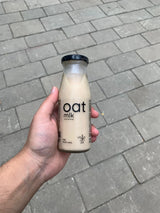 Portable 200ml glass bottle of creamy OatMlk, a convenient ready-to-drink healthy snack for office commutes and travel.