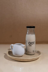 A collection of sleek OatMlk 200ml premium glass bottles, showcasing a convenient trial pack of pure oat milk.